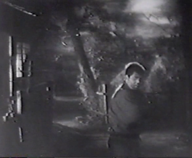 A brooding man in peasant clothes on a road at night