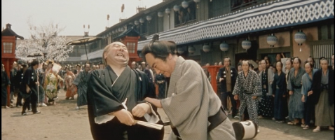 The middle-age man, Hyogoya, is fatally stabbed in the foreground by the man in the sedge hat, while the crowd in the background flees in all directions