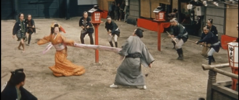 Jirō, still brandishing his sword, has gotten hold of Otsuru's obi and she twirls around as she struggles to escape him, as guards struggle to get close enought to stop him