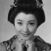 A young woman in traditional Japanese kimono and hairstyle, in closeup, smiling into the camera