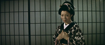 In ancient Japan, a beautiful young woman is seen in a medium close shot looking towards the ground, her hands folded on her chest