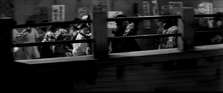 A group of women, including a woman in an apron, are seen running over a footbridge in Tokyo