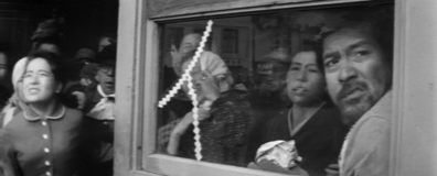 Screenshot image of the destitute central character, a bearded, ragged man, Inukai, looking at something out of a half-broken window; members of the crowd around him, who are poorly-dressed, are looking in the same direction with varying degrees of surprise