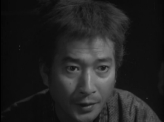 Picture of a surprised-looking Japanese man, shown against a dark (night) background, wearing clothing from Japan's feudal era