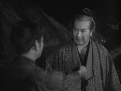 Two Japanese men in the feudal era confront each other at night on a road; the smaller man holds out something in his hand to the larger man, but the latter looks at him with scorn