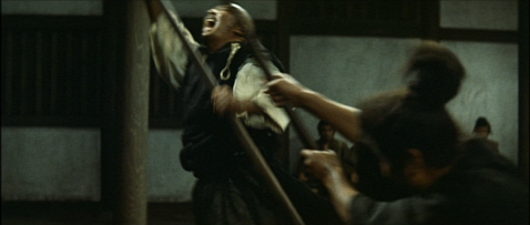 One young Japanese man, using a wooden sword, attacks an older, larger man: both are wearing costumes from the feudal period