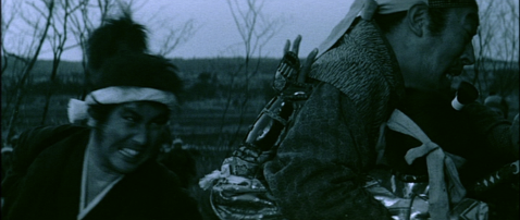 A fierce young Japanese man in period costume is seen putting his sword through both a middle-aged man and a young boy that the man is holding and trying to protect