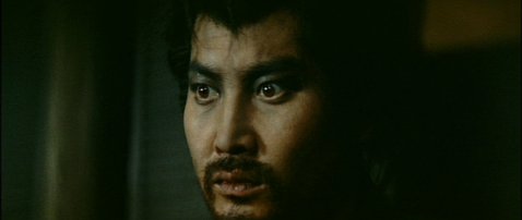 Closeup of a bearded Japanese man, looking with anxiety towards something outside camera range