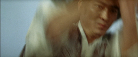 In a blur of motion, a young Japanese man moves his arms toward something or someone out of camera range