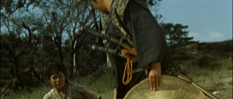 Against an outdoor scene, a partly-seen adult Japanese man stands over a Japanese boy of about ten, whom he's just pushed to the ground