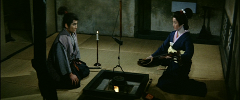 The Japanese man and woman now sit opposite one another with the fire between them, as she shows him the broken musical instrument